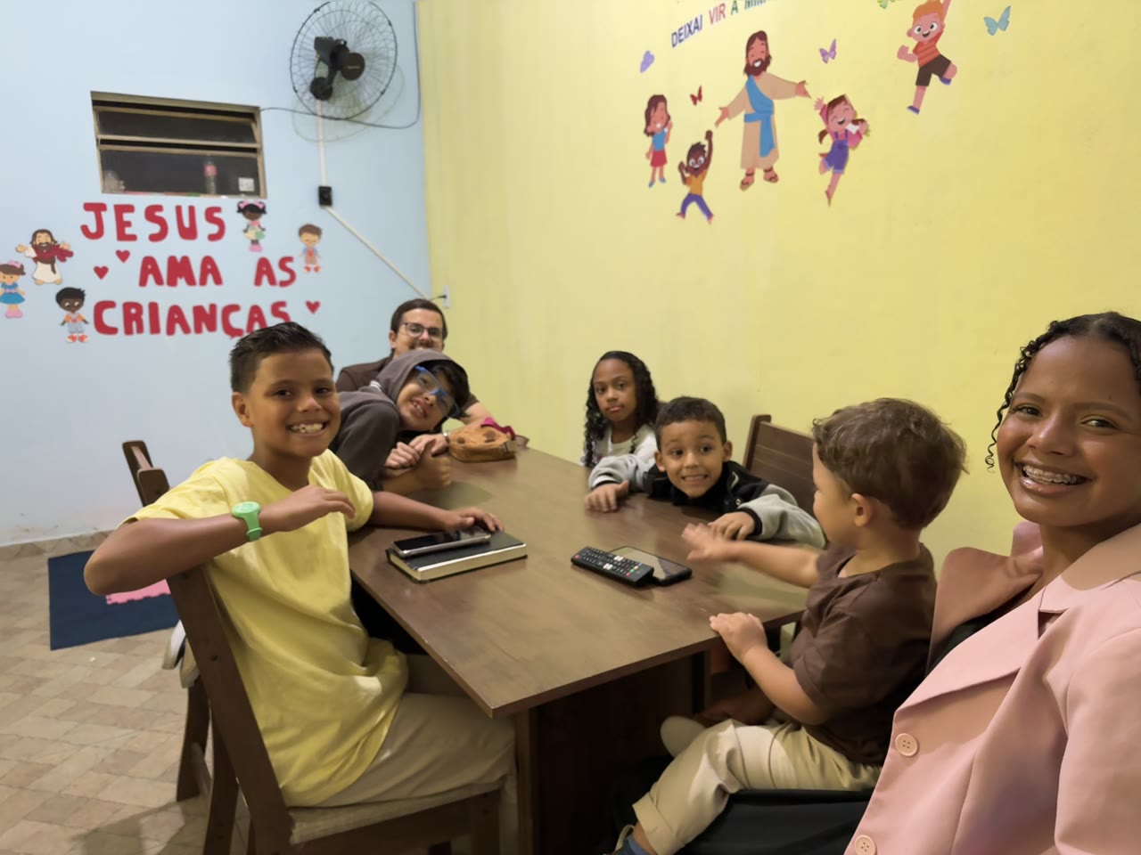 Crianças e voluntários da Rede Kids reunidos em volta da mesa